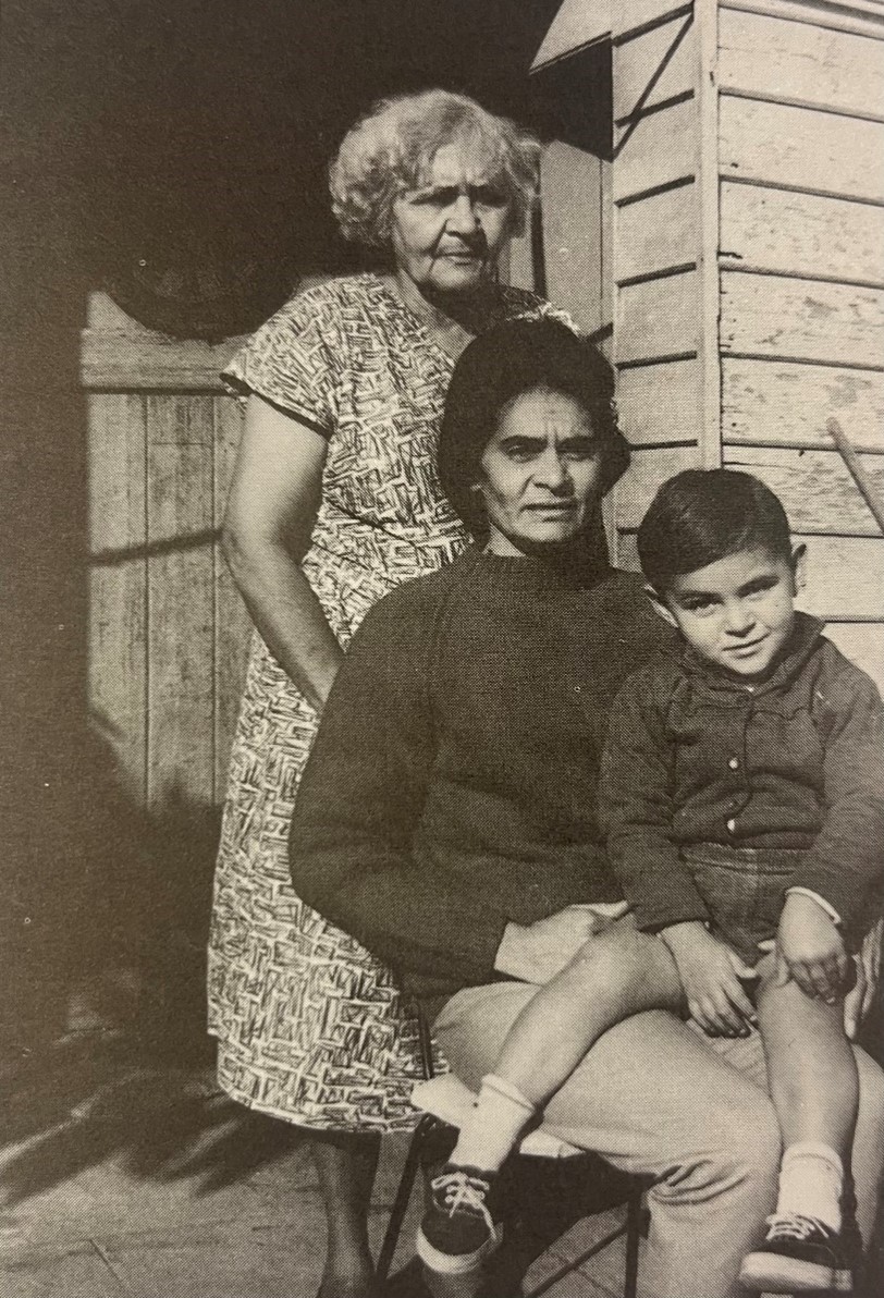 Older woman standing behind a younger woman seted with a child on her lap