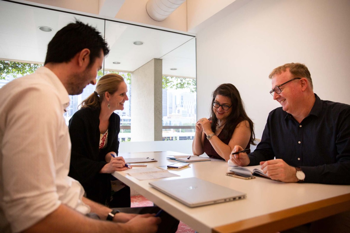 Group of four people at a desk in a meeting room