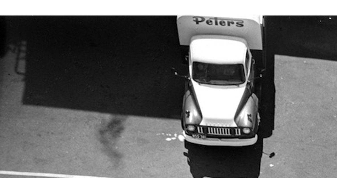 A Petere's Ice Cream truck driving out of a building with a corrugated iron roof