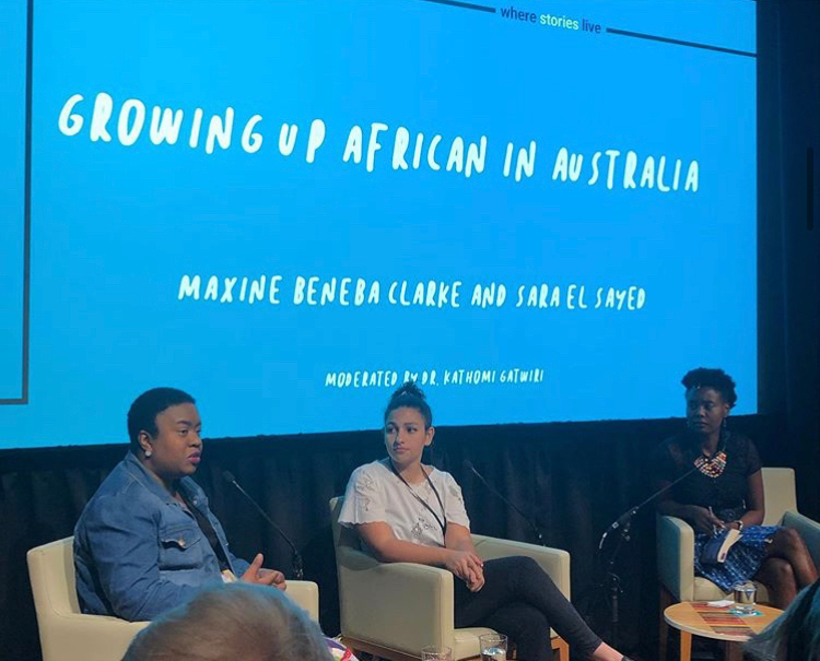 Maxine Beneba Clarke, Sara El Sayed and Kathomi Gatwiri sit in front of a blue screen that says "Growing Up African in Australia".