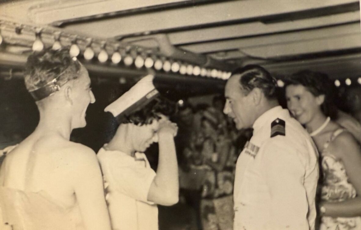 Joyce Tuesley and the group of cross-dressing men were presented with prizes by the captain of the SS Oronsay, although Joyce Ann Tuesley still appears self-conscious about the attention brought by donning the uniform of one of the captain’s sailors. This photograph is from the Tuesley Family Photographs collection, taken on a cruise on the ship S.S. Oronsay in 1955 to New Zealand and Fiji.