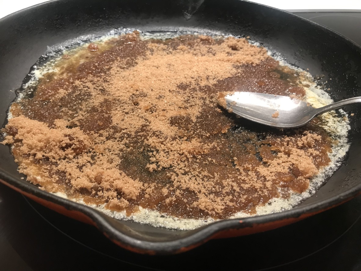 skillet pan with a silver spoon on  a mix of melted butter and brown sugar 