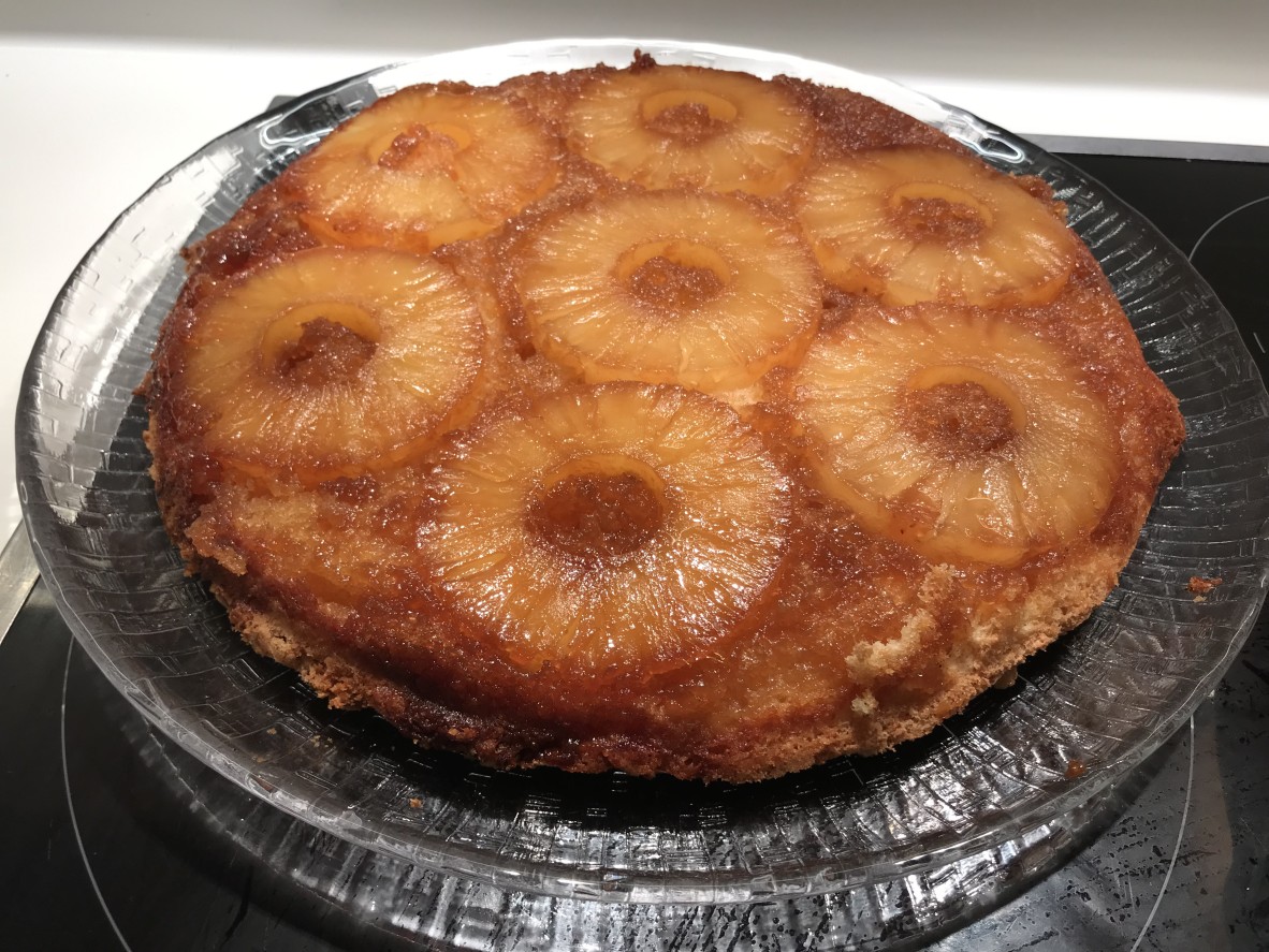 cake topped with 7 pineapple slices on a glass platter 