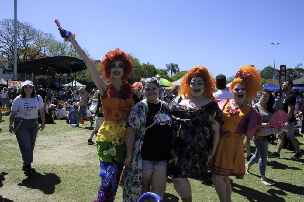 Three drag queens and a visitor at New Farm Park Pride Fair Day 32310 Brisbane Pride Fair Day photographs 2019 John Oxley Library State Library of Queensland