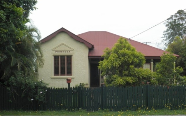 A house with a red roof and several trees in the garden