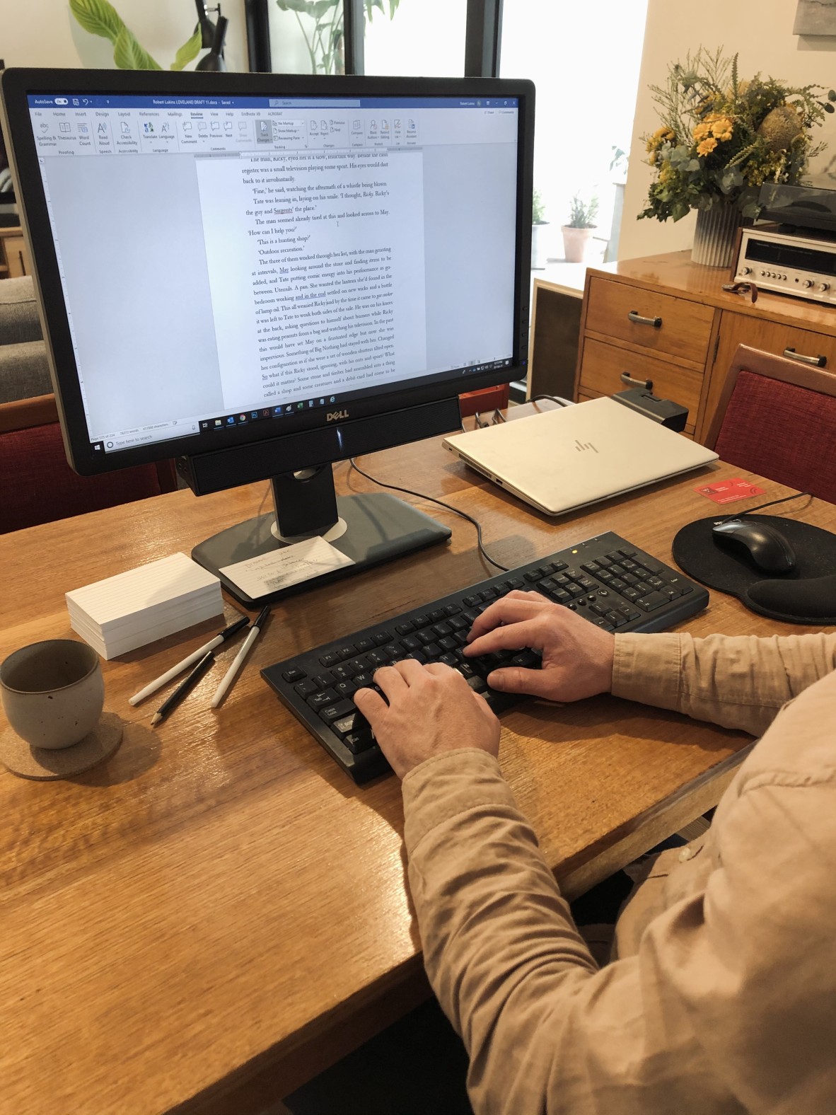 A close up of a computer screen on a wooden desk and Robert's hands typing at the keyboard