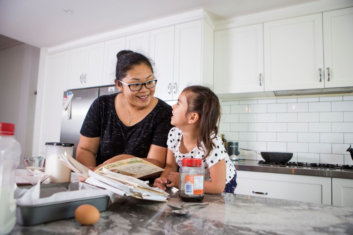Mother and child reading a cookbook in their kitchen