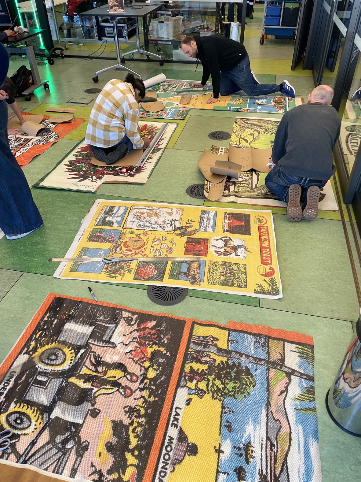 A photo of people cutting vinyl material on the floor
