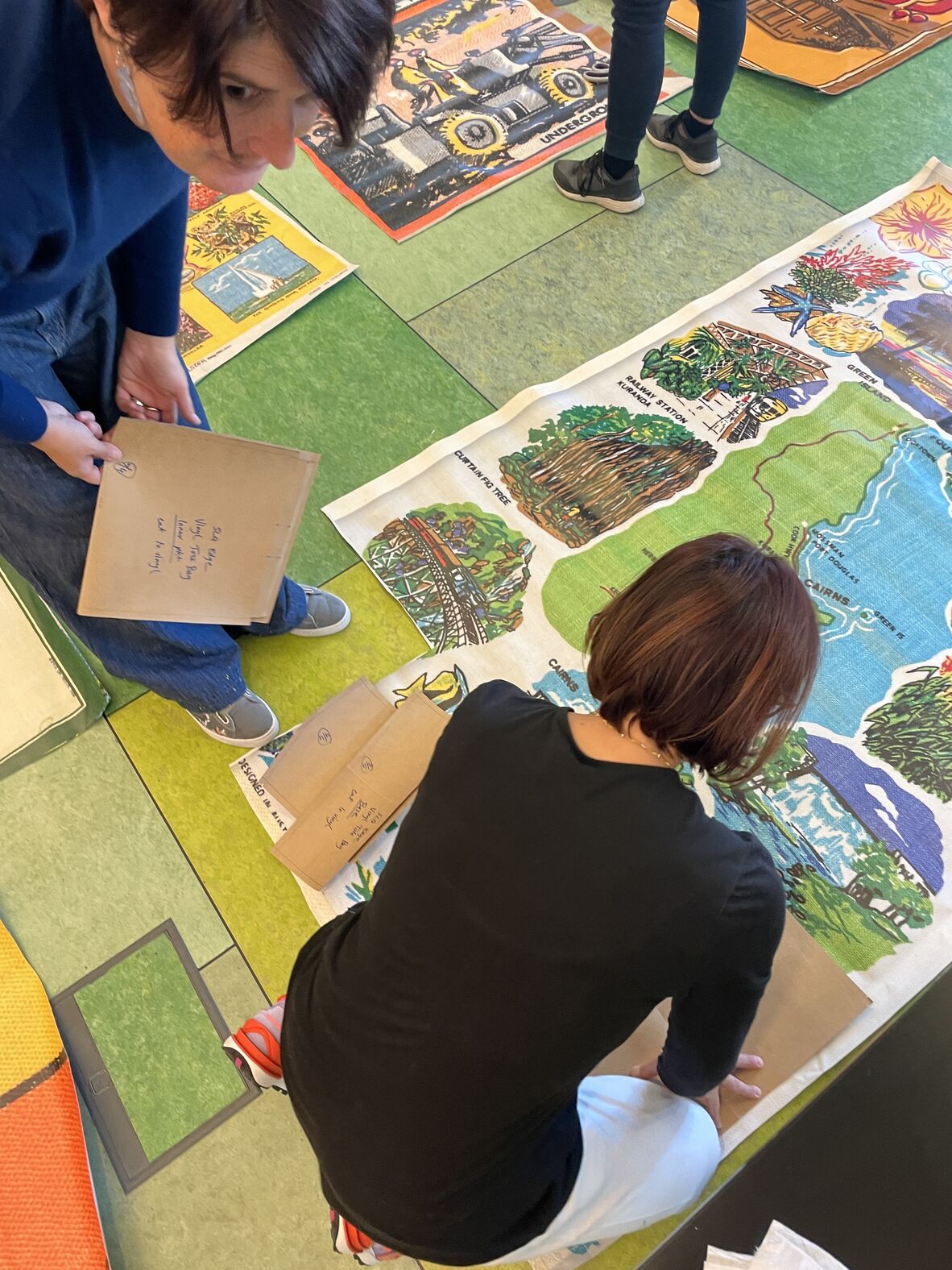 A photo of people cutting vinyl material on the floor