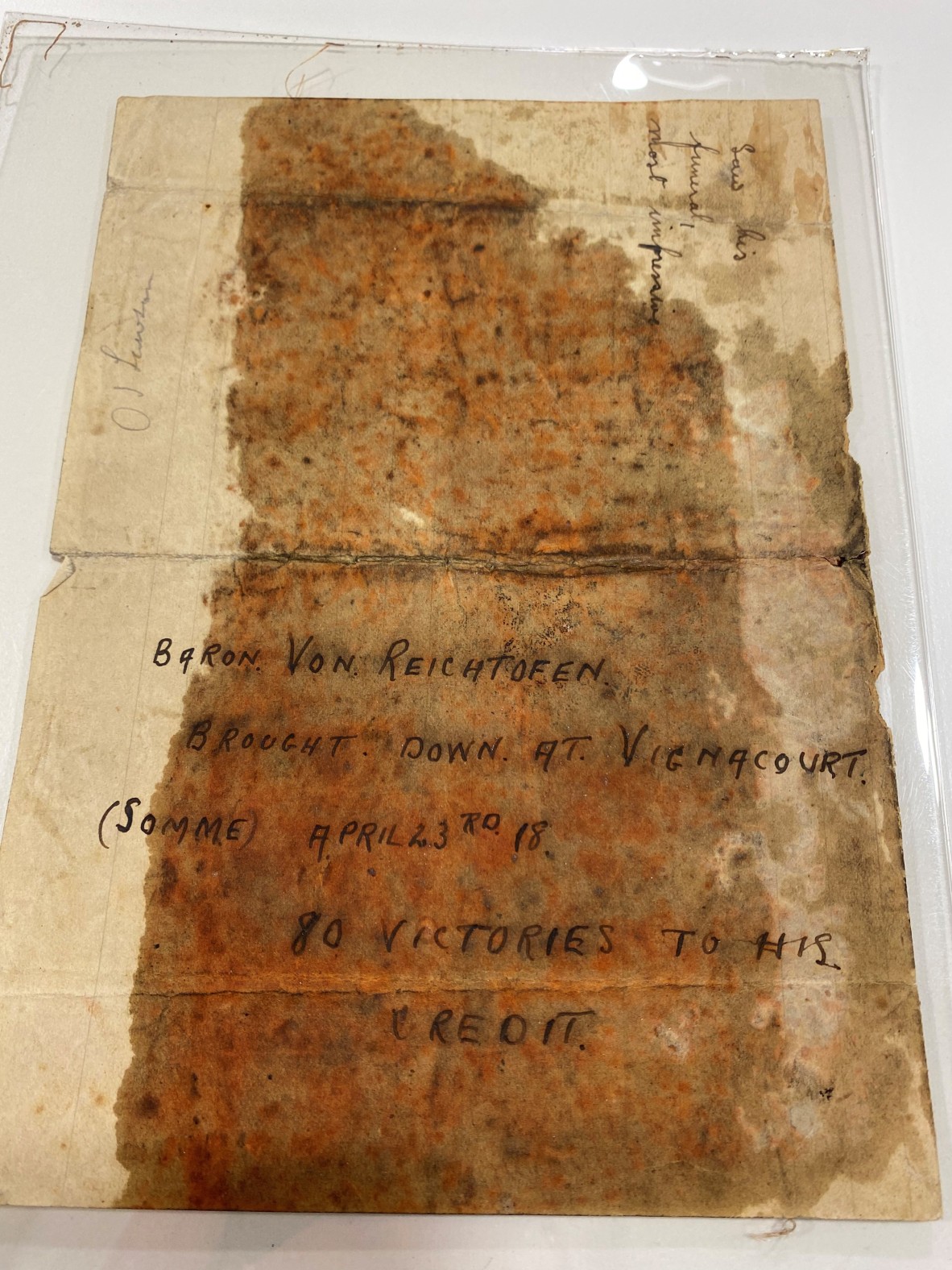 a very old and red-stained note houses a piece of WW1 Aeroplane. It reads: Baron Von Reichtofen (Sic), Brought down at Vignacourt (Somme) April 23rd, '18