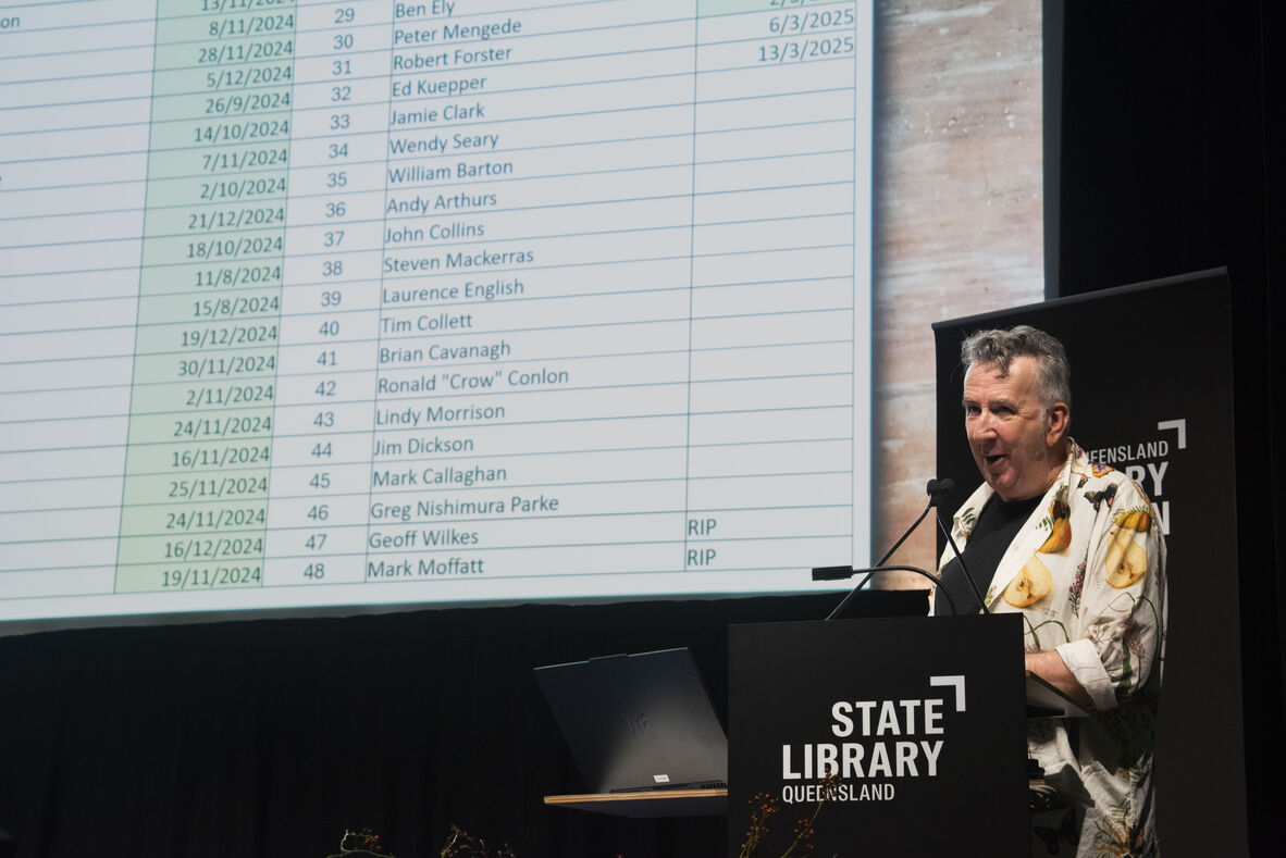 Dr John Willsteed presenting at Research Reveals, sharing a spreadsheet of Queensland musicians he interviewed for his project, Dive For Your Memory.