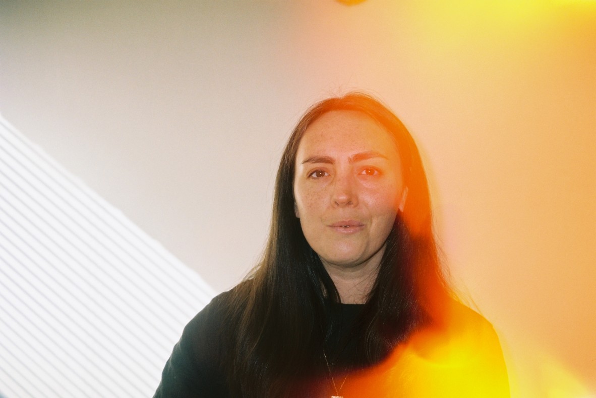 Susie Anderson - a photo of Susie wearing black, against a cream coloured wall