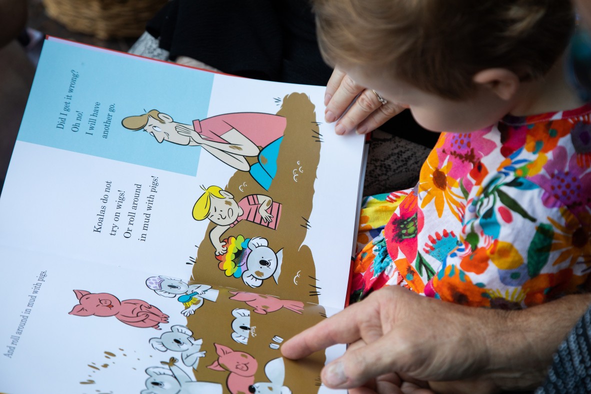 Child and family reading "Koalas like to..." book