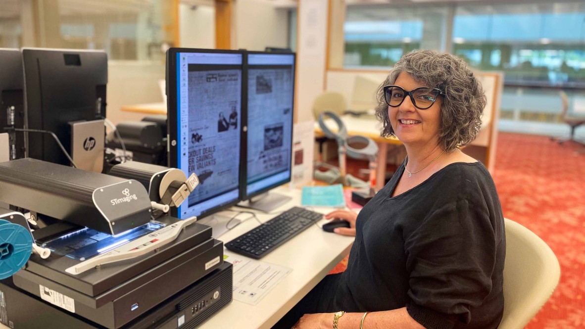 Woman sitting at microfilm machine in library