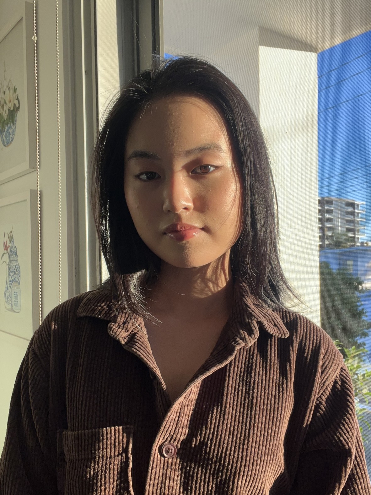 Photo of Sara Allan-Park who stands in front of a window. She wears a brown corduroy shirt.