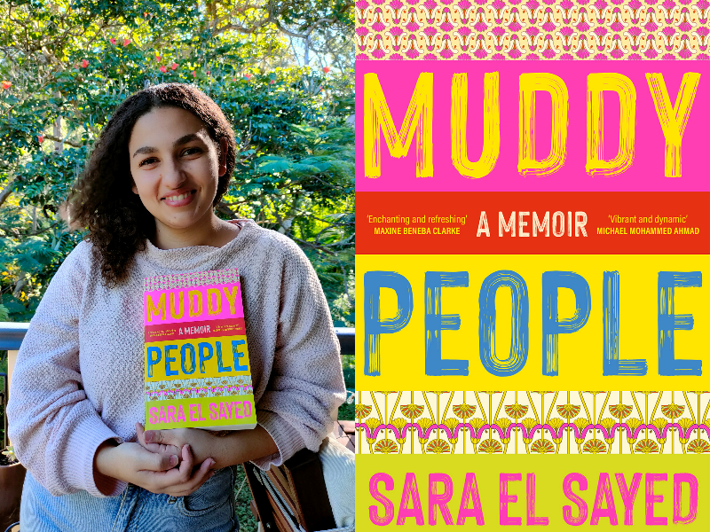 Sara El Sayed wears a jumper and jeans she stands outside in front of a tree and holds her book Muddy People