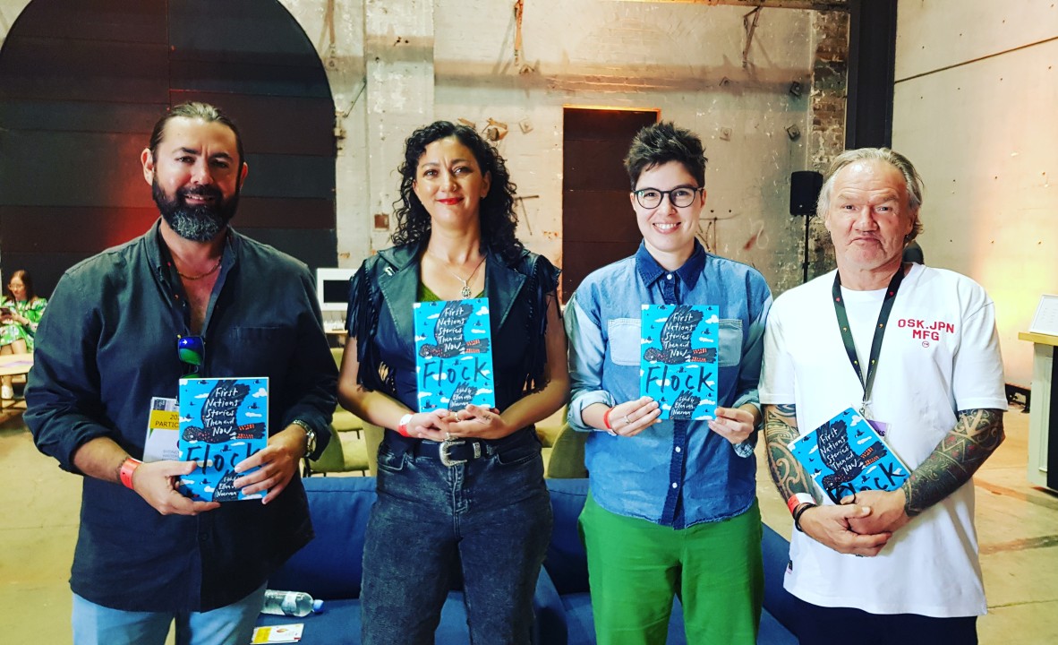 Adam Thompson Mykaela Saunders Ellen van Neerven and Tony Birch stand in front of a couch smiling and holding copies of the anthology Flock