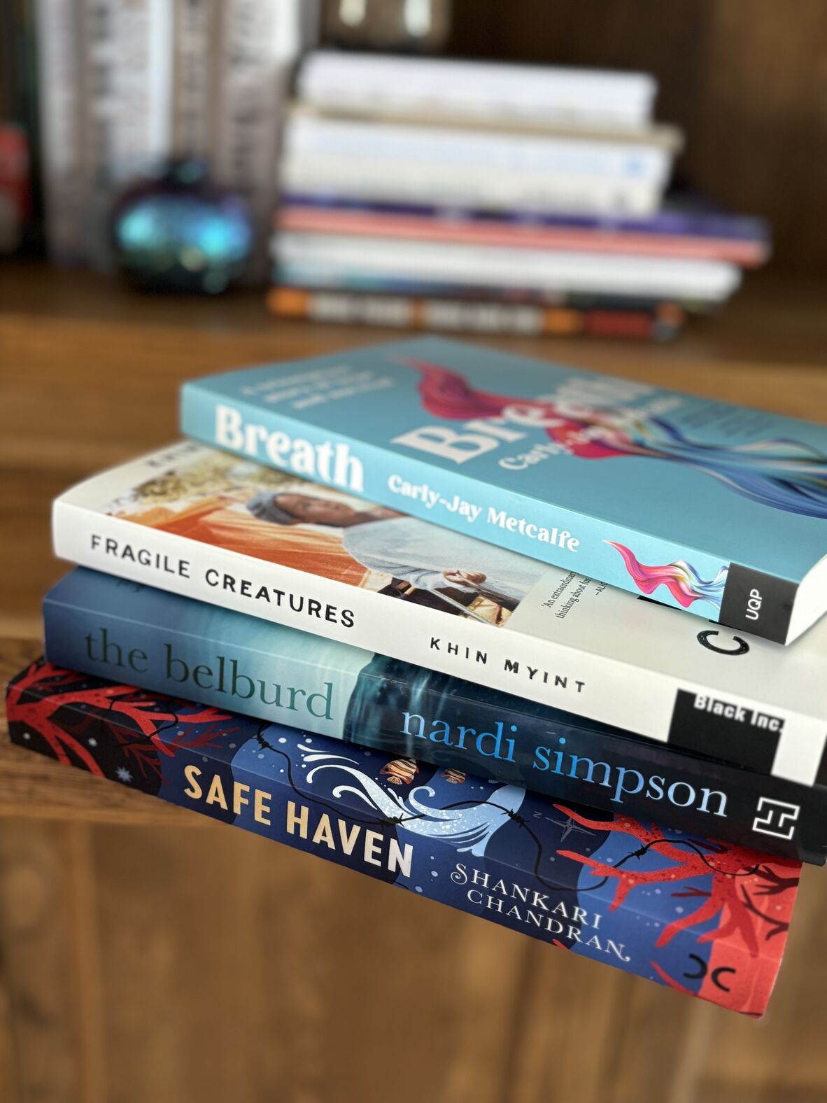 A stack of books on a table: Breath, Fragile Creatures, The Belburd, and Safe Haven