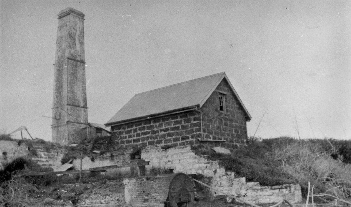 Black and white photo of sugar mill ruins on St Helena Island, 1928. It shows a stone building beside a tall chimney.