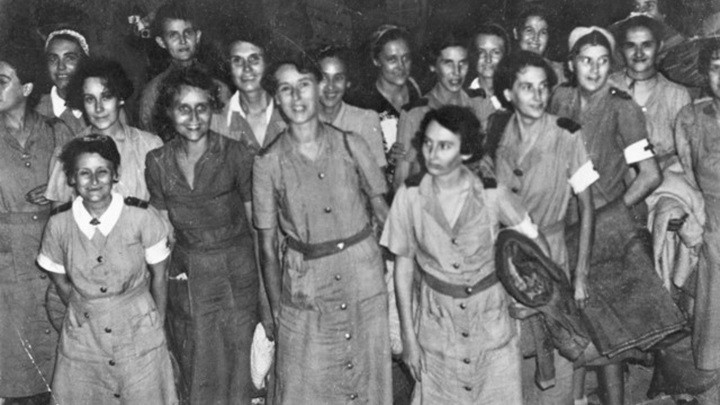 Group of 24 women in uniforms standing together. Some are smiling.