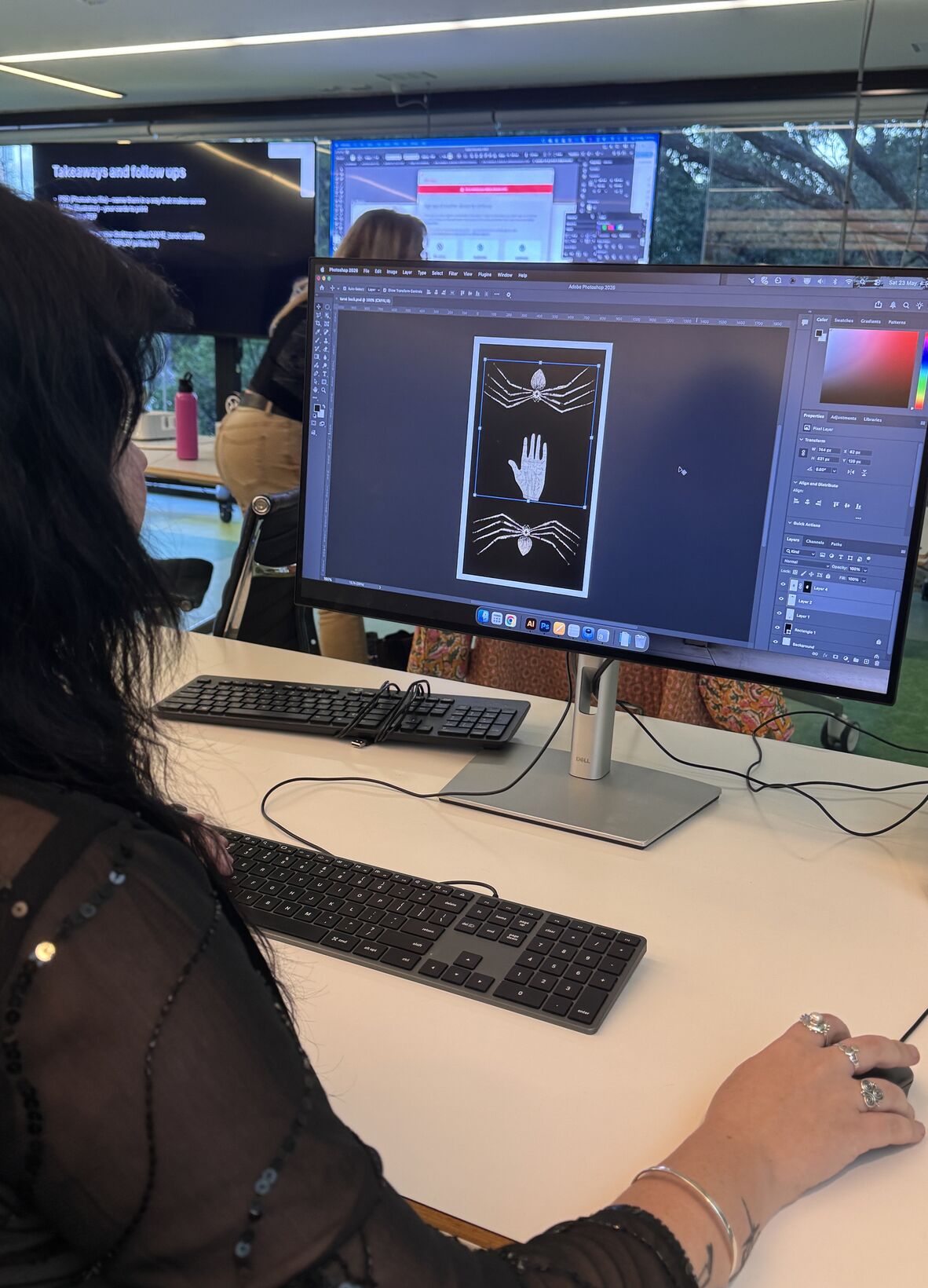 A photo of a woman working on a computer designing a Tarot card