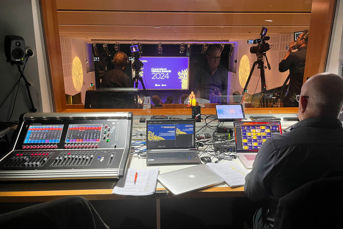 Man working behind the scenes in a control room during a ceremony. 