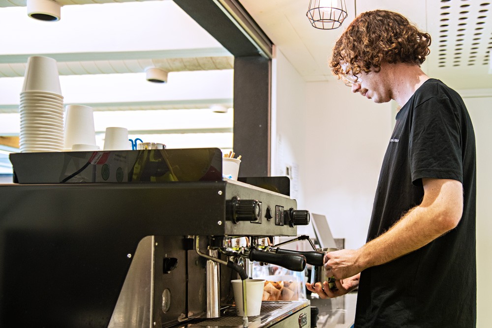 Staff member making coffee with a coffee machine at the Brink.