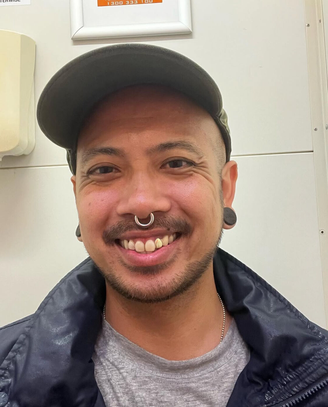 A photo of a man with a hat on an piercings