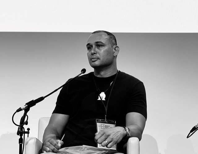 A black and white image of Thomas Mayor sitting down and speaking at Brisbane Writers Festival in 2021
