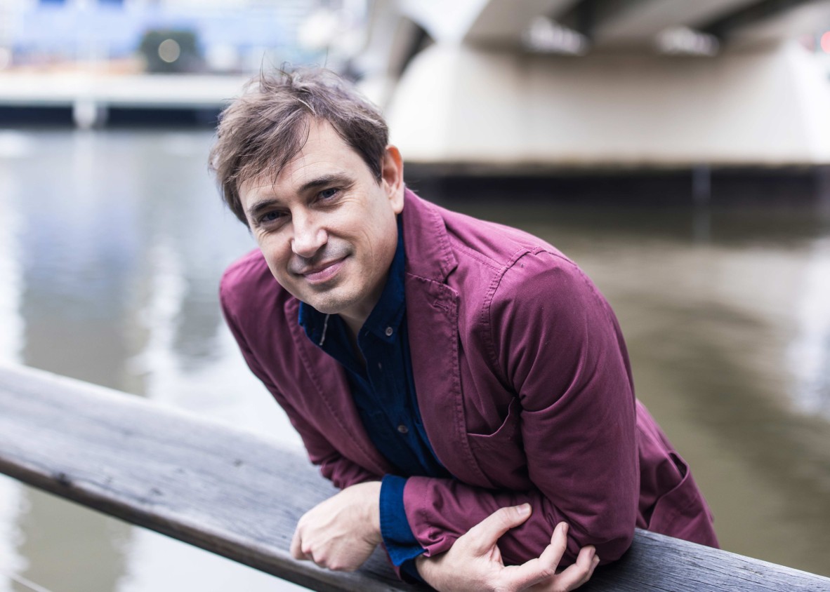 Man leaning over railing near bridge