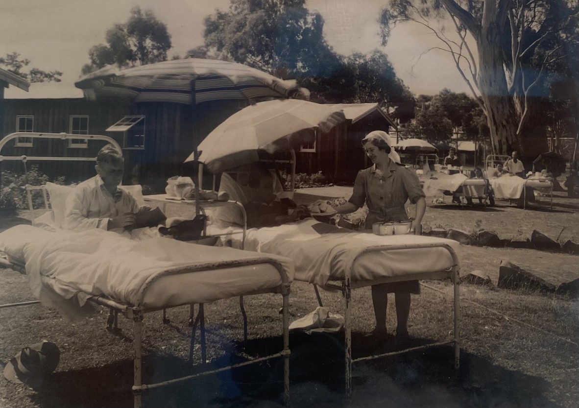 Black and white photograph of soldiers in hospital beds outside a hospital. 