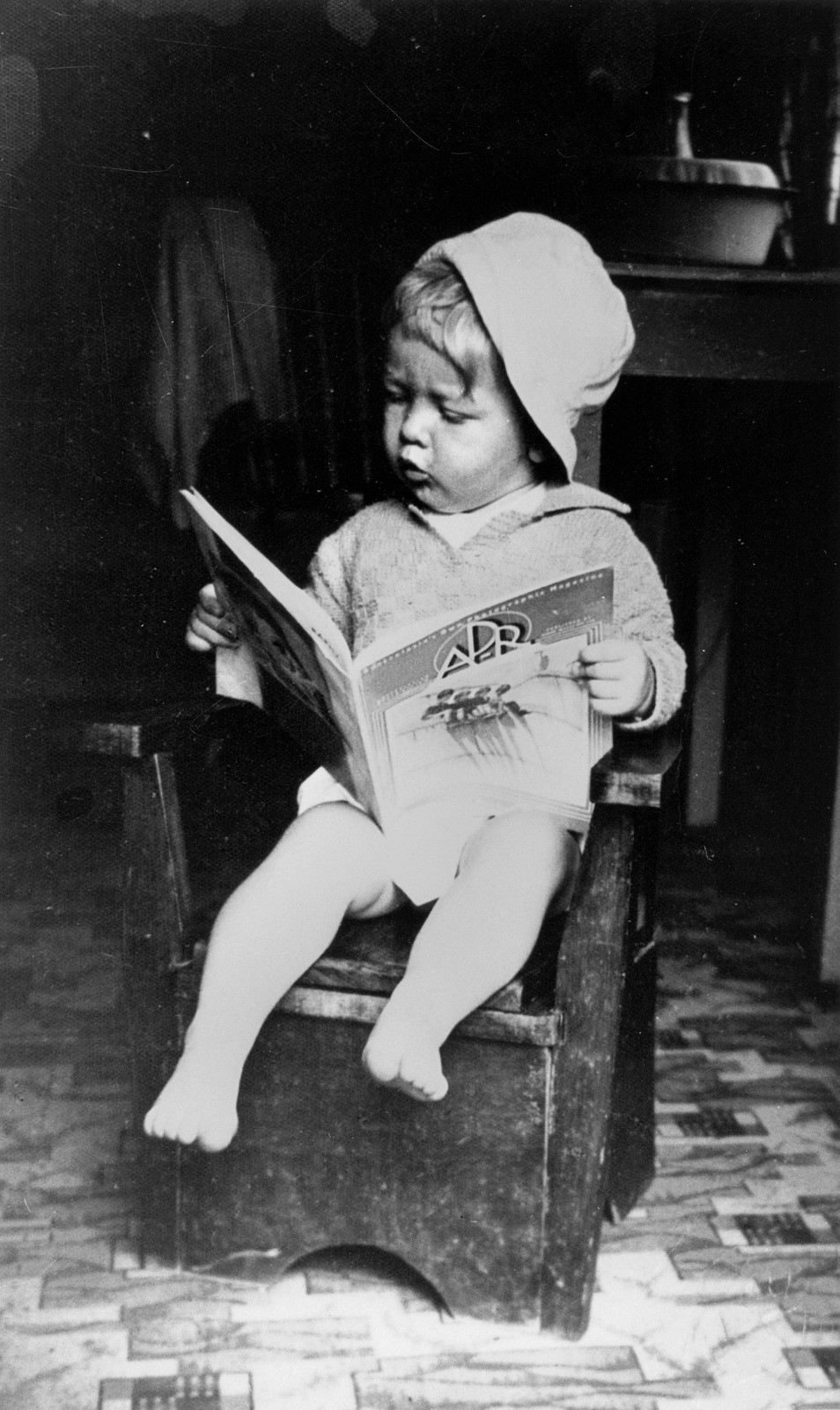 A picture of a small child sitting on a seat reading