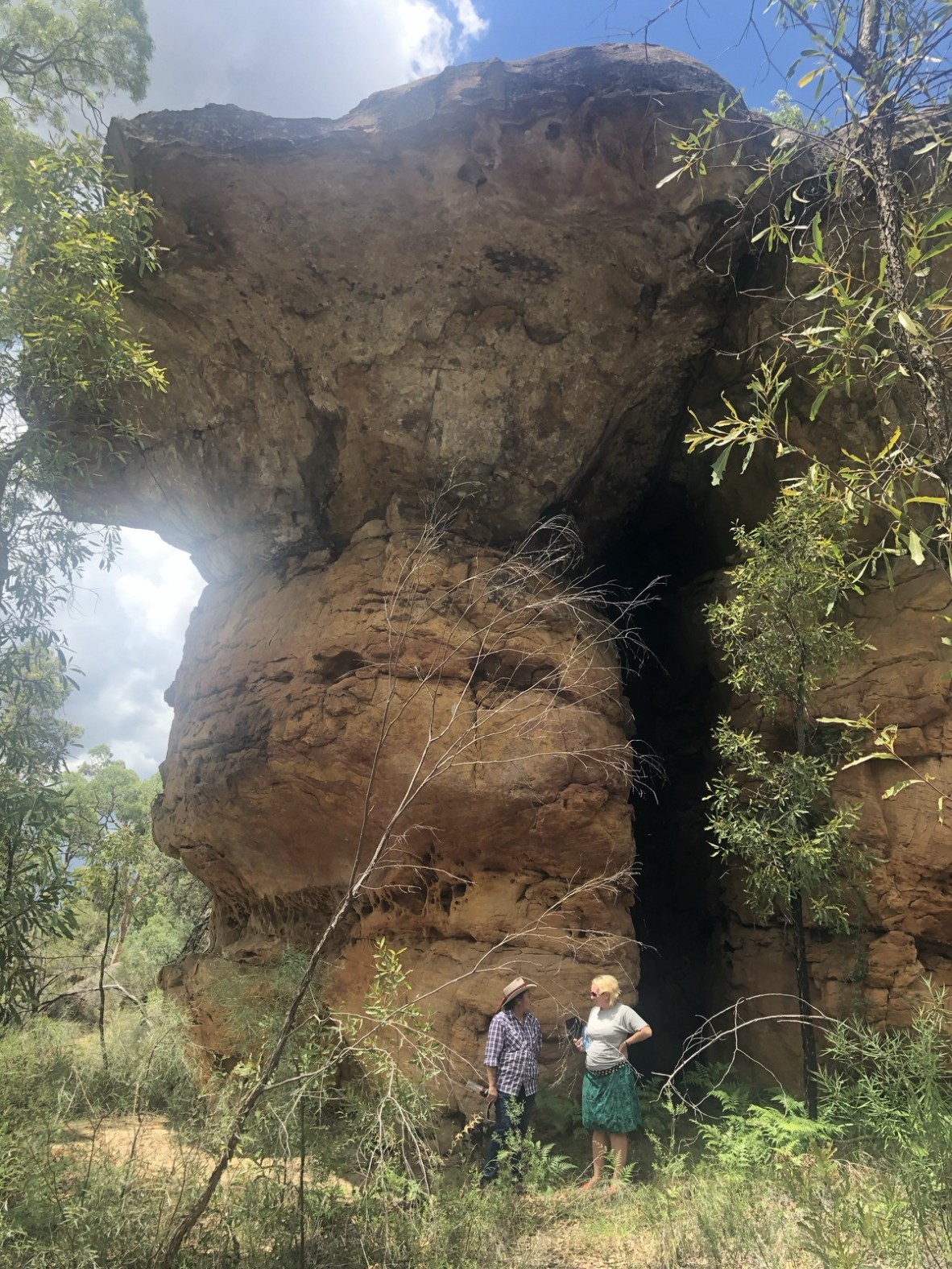 Keelen Mailman explains the history and importance of Dickradee to Holly Zwalf while standing next to a large sandstone formation on Mount Tabor Station, Queensland, February 2020