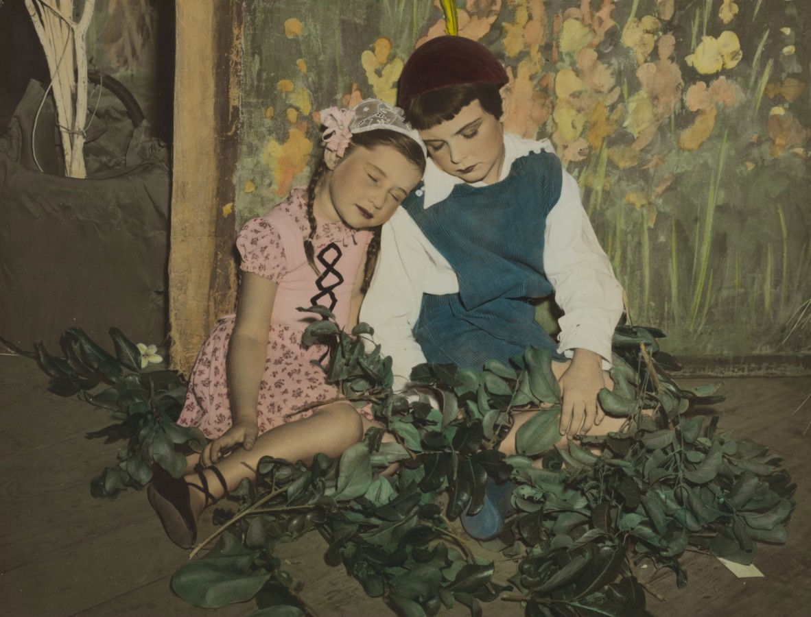 two children appear resting against a theatre backdrop of a forest for the play Babes in the Wood in 1952