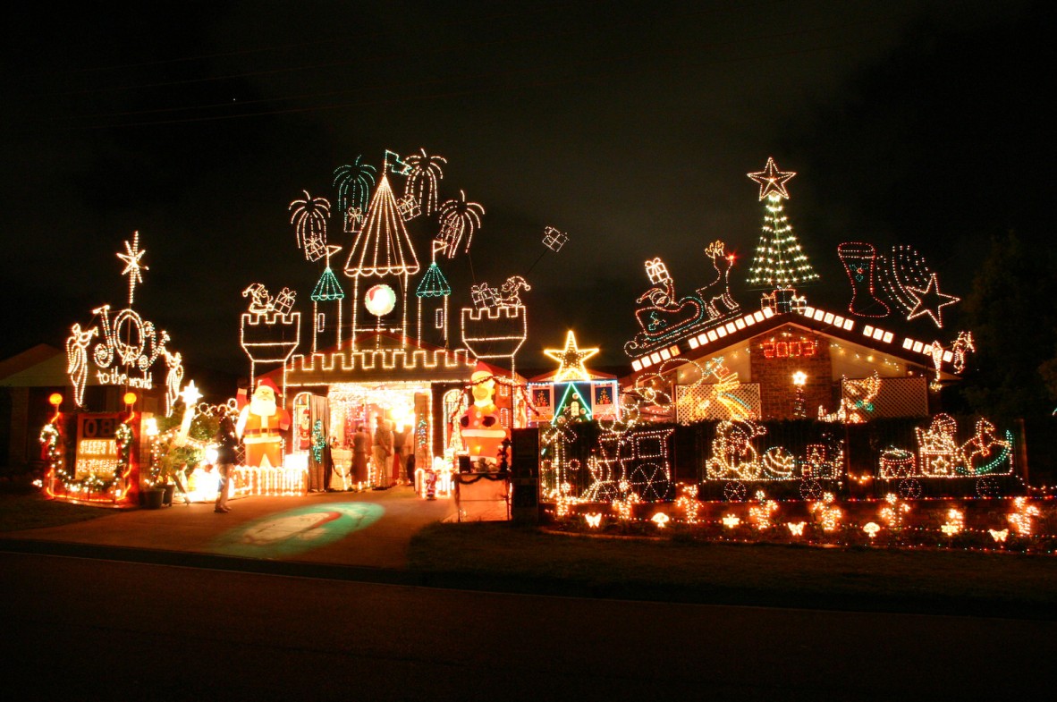 suburban house lit up with christmas lights including castle turrets, stars and a christmas tree.