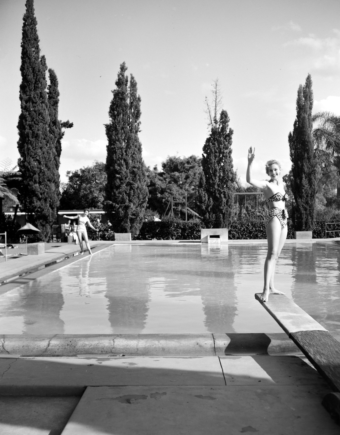 Two women posing in bikinis at a swimming pool.