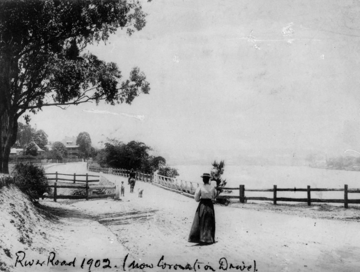 A woman walks down a dirt road next to the Brisbane River 