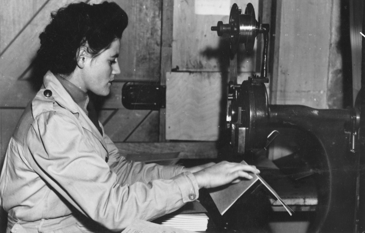 young woman in light coat operates machinery as part of the women's land army 
