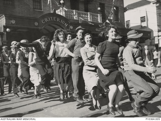 Women and service men dancing in a line