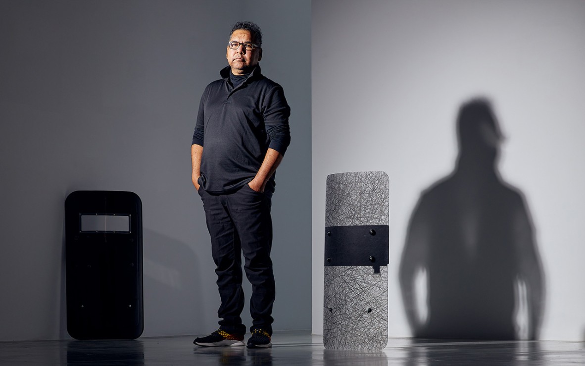 artist standing between riot shields resting on ground