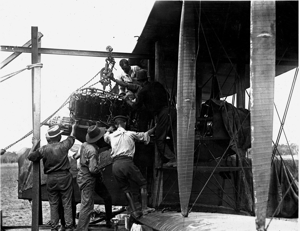 Aircraft engine being installed in a Vickers Vimy biplane bomber G-EAOU by mechanics.