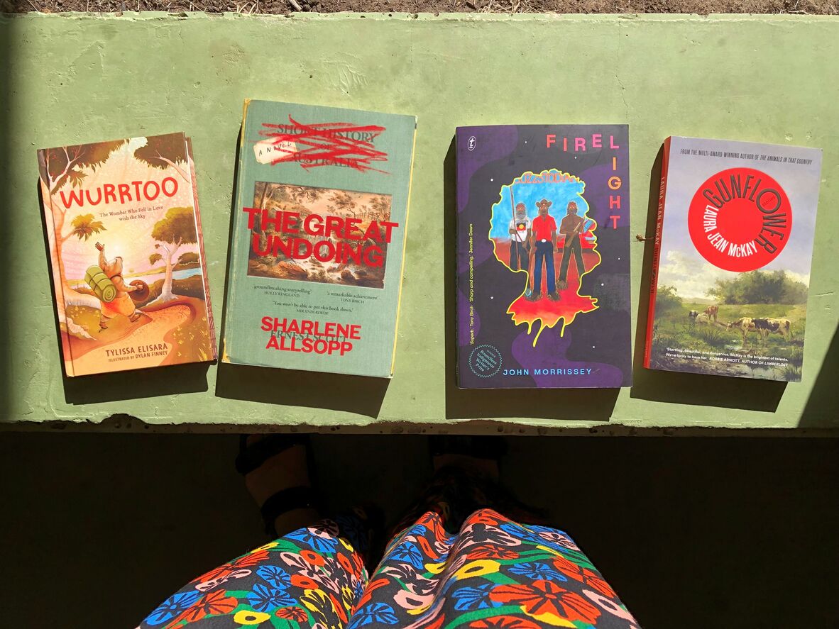 Four books (Wurrtoo, The Great Undoing, Firelight, Gunflower) on a green bench