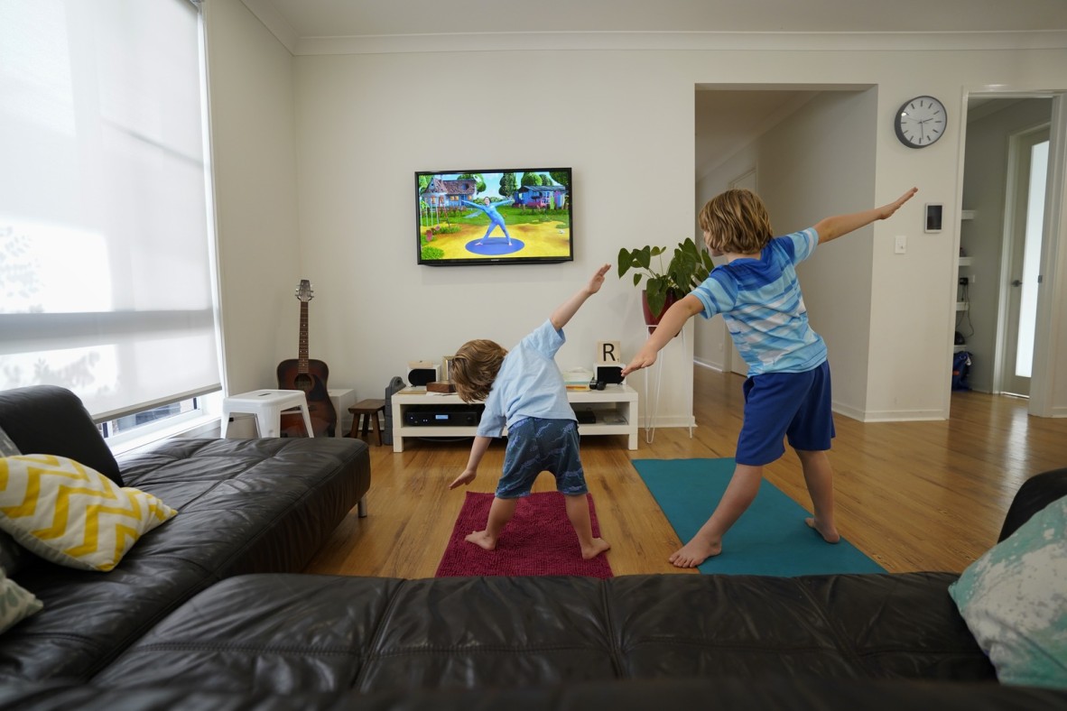 Two children in a loungroom doing yoga in front of TV