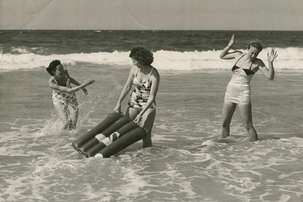 Young women playing in the surf splashing each other
