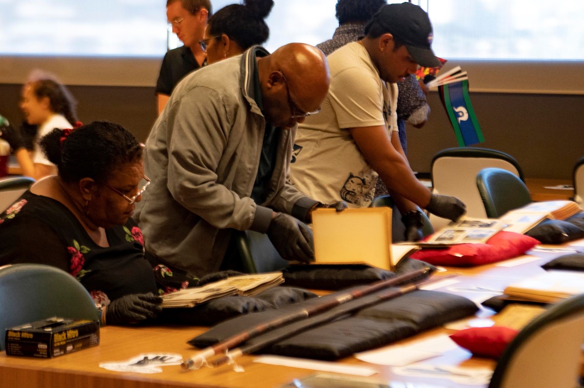 First Nations men and women viewing collections in a library