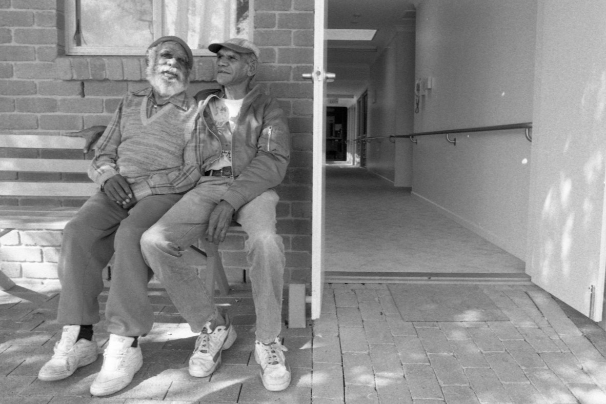 Two aboriginal men sitting outside the Ny-Ku Byun aged care facility in Cherbourg, Queensland.