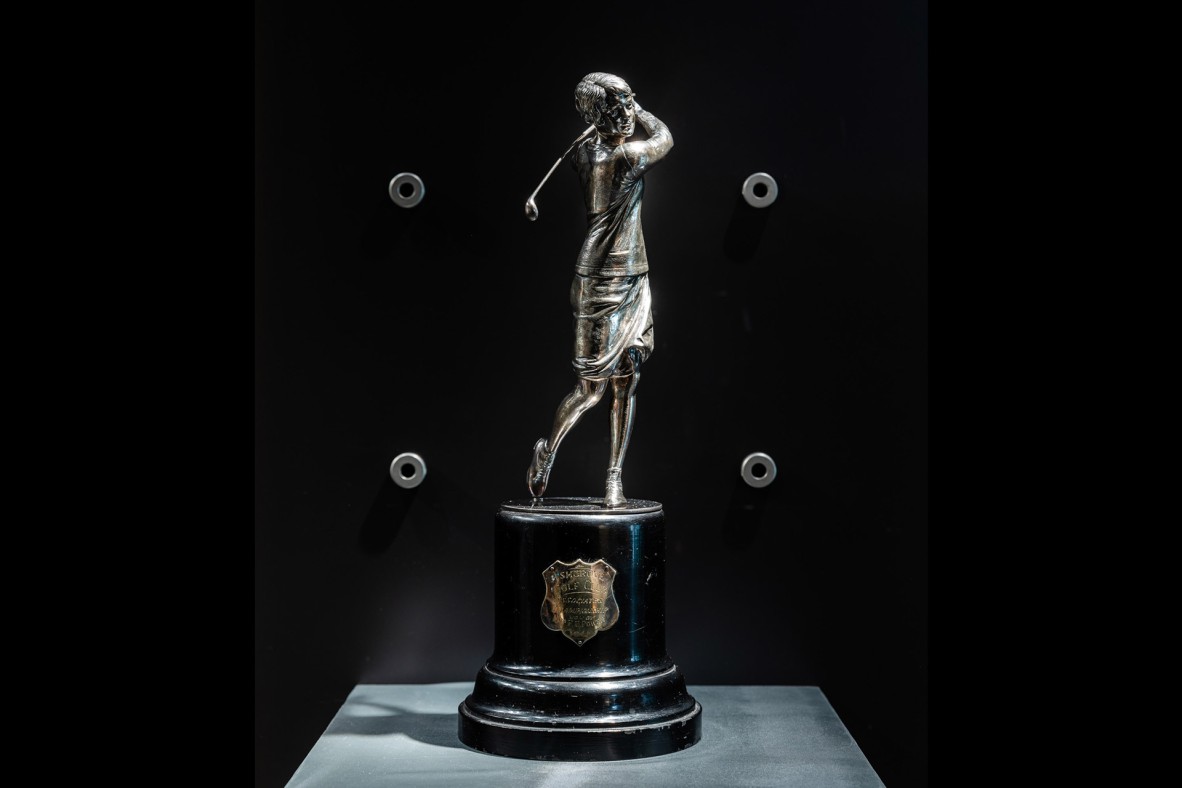 Silver golfer figure on wooden base with attached silver plaque.