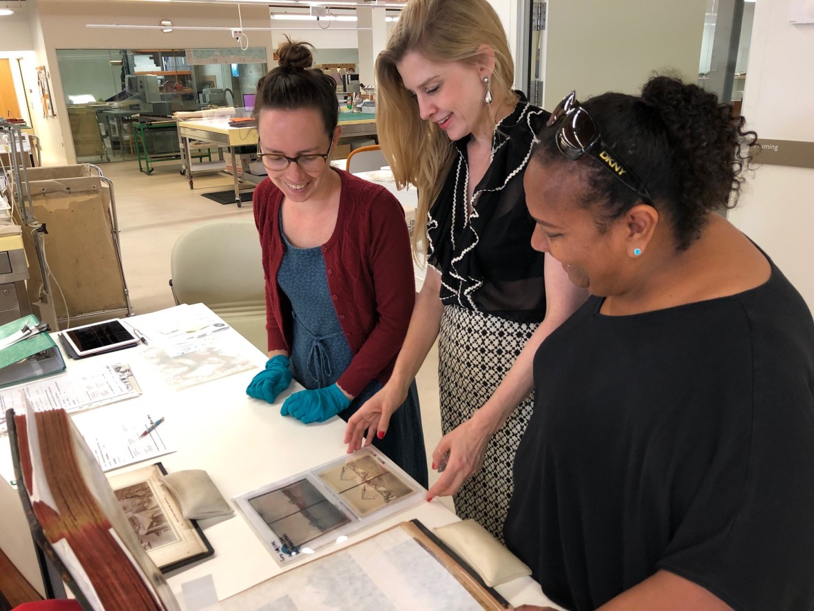 Three SLQ staff looking at photographs
