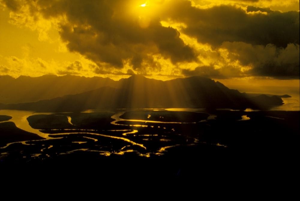 yellow sunrise over hitchinbrook island with sunlight reflected off a river system in the foreground