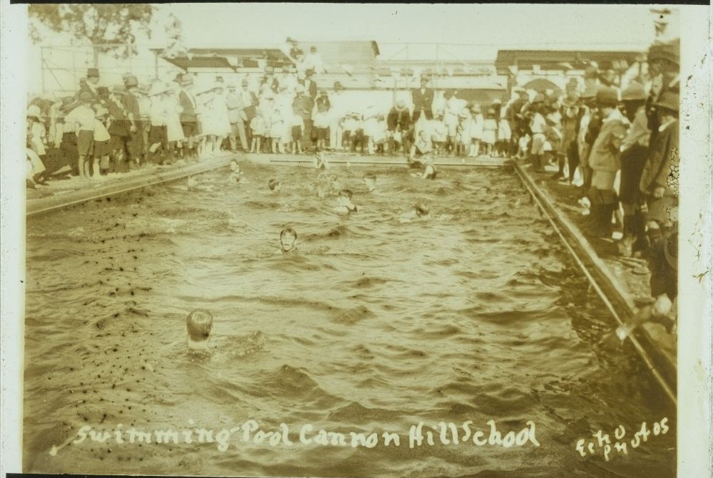 Children swimming surrounded by a crowd at the opening of the Cannon Hill State School swimming pool, 9 December 1922. John Oxley Library, State Library of Queensland